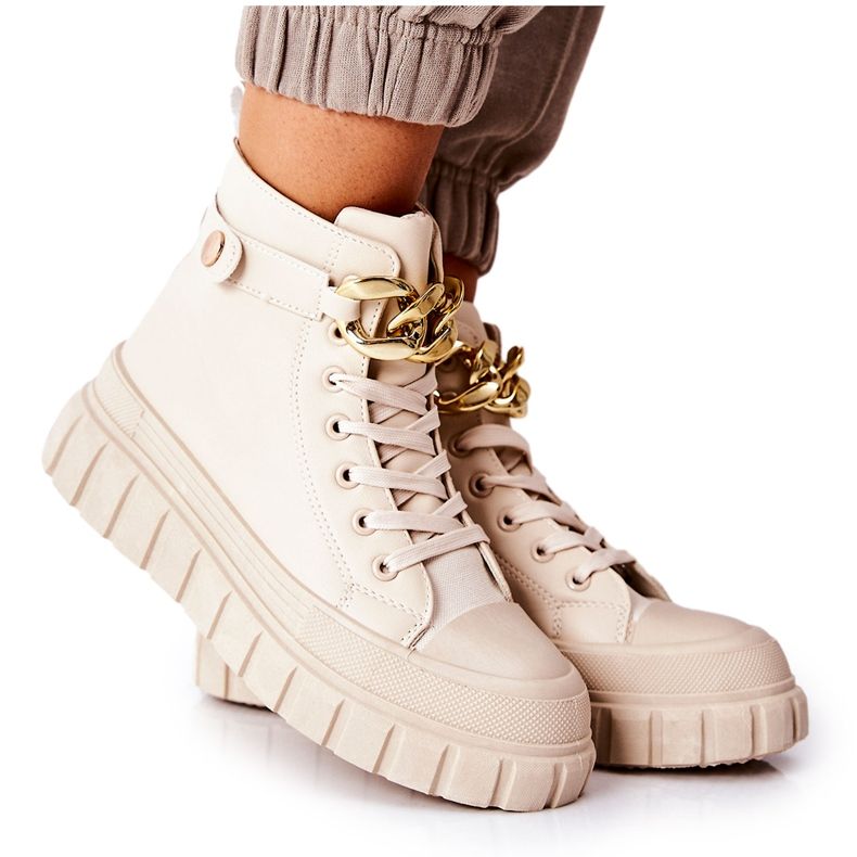 Korkeat tennarit beigellä jalustalla kultainen