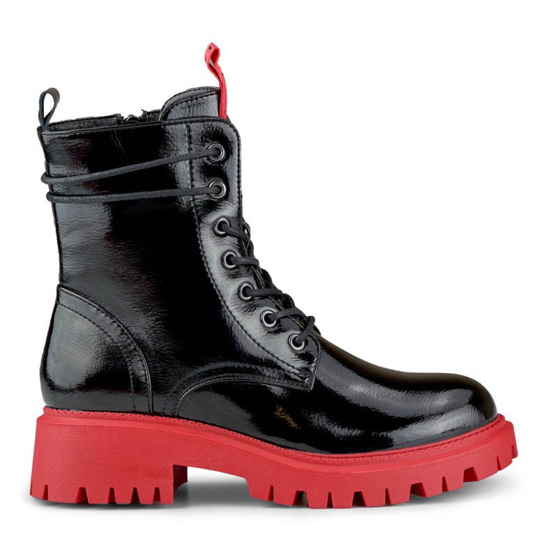 Lakatut naisten mustat työsaappaat punaisella pohjalla