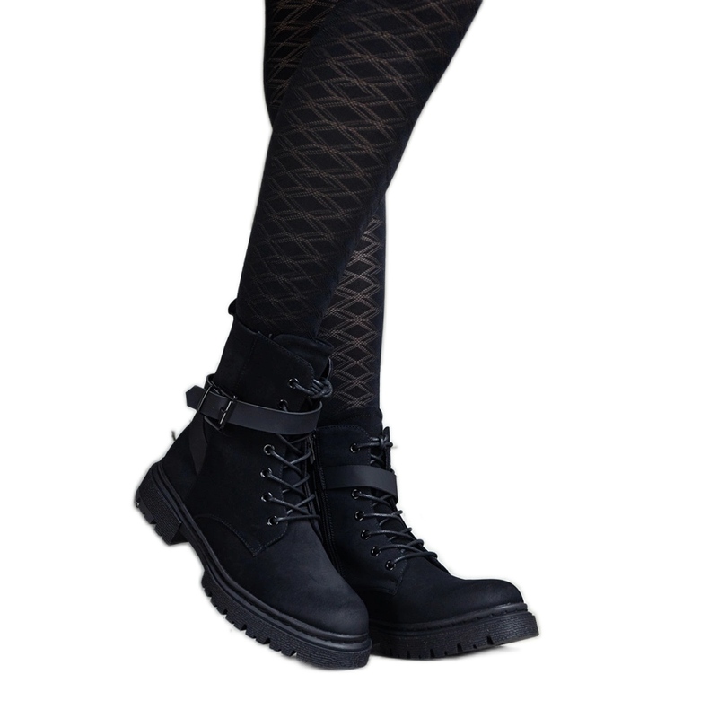 Mustat eristetyt vaelluskengät, joissa kulumia ja polvihihna