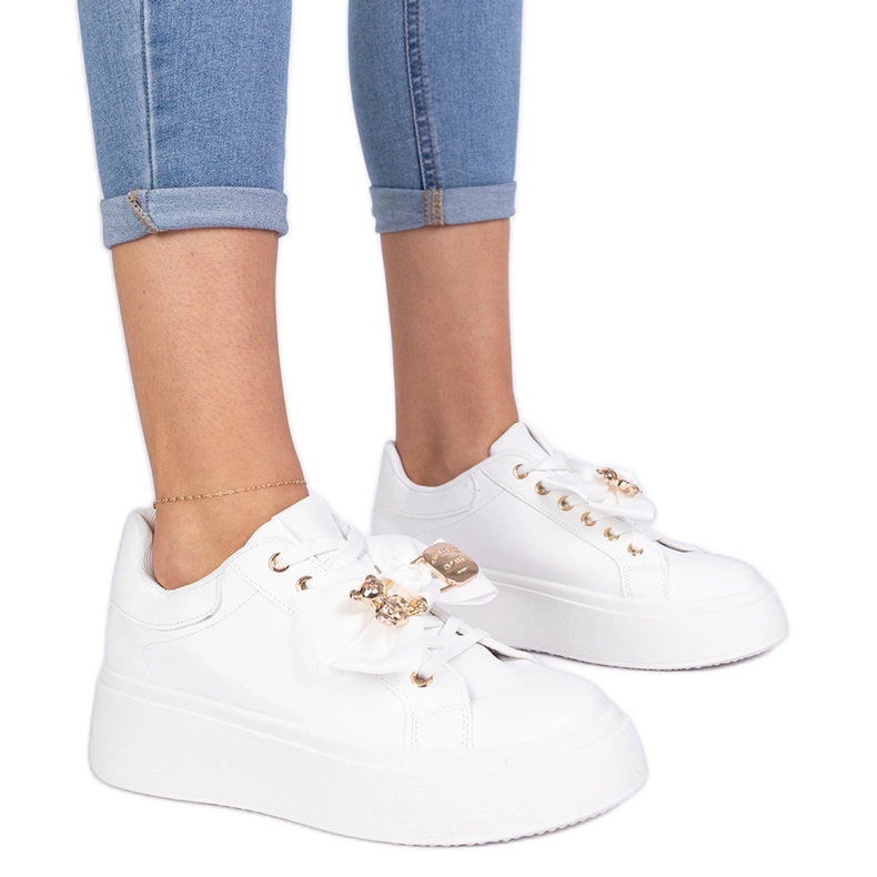 Valkoiset lenkkarit, jotka on koristeltu keulalla ja kultaisella nallekarhulla valkoinen