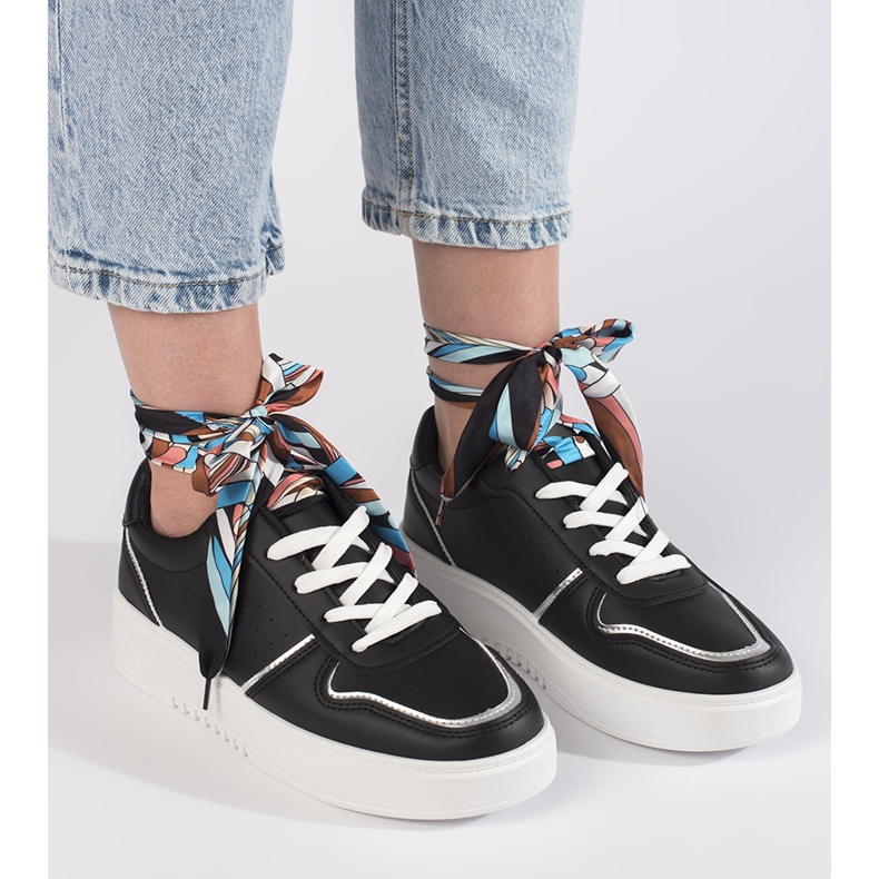 Mustat naisten tennarit, jotka on sidottu nauhalla 1