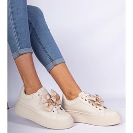 Beige -lenkkarit, jotka on koristeltu keulalla ja kultaisella nallekarhulla 1