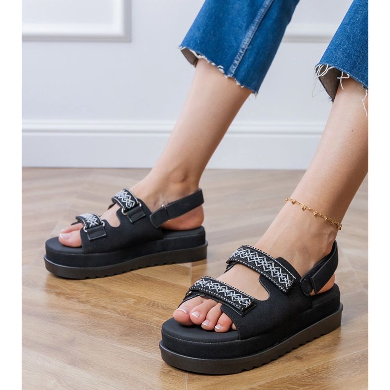 Mustat sandaalit, joissa on brodeeratut raidat laiturilla 1